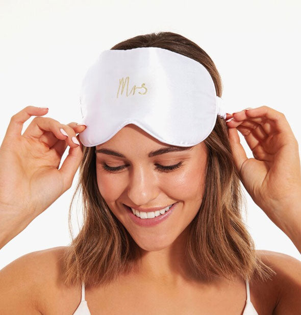 Smiling model wears the Mrs. sleep mask up over her eyes