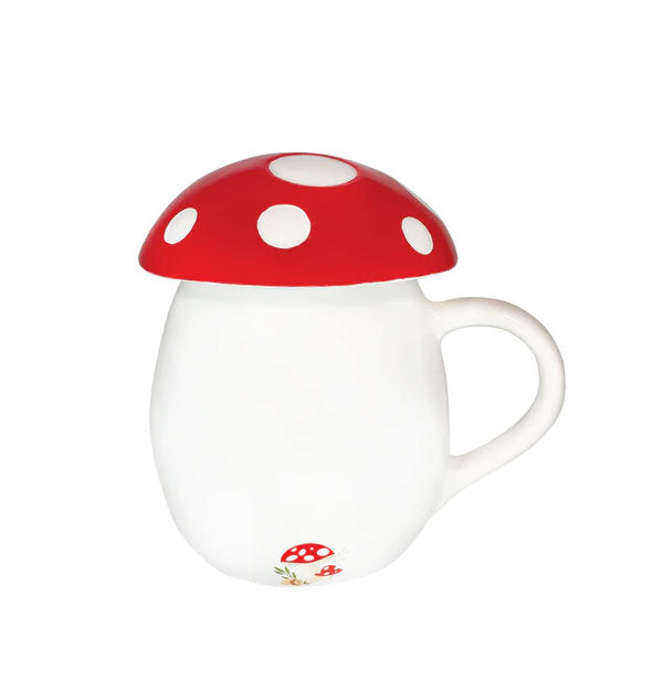 Rounded white mug with red with white spotted mushroom cap lid and small mushroom graphic near mug's base