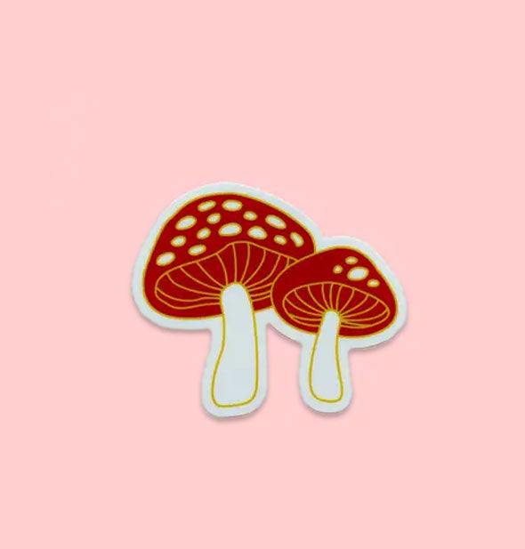 Red and white mushrooms sticker with yellow outlines on a pink surface