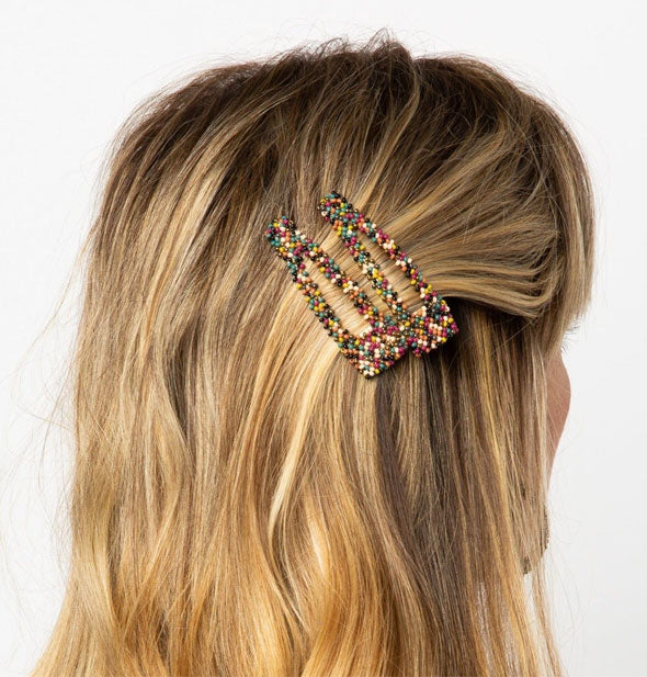 Model wears two multicolor beaded hair clips in a swept-back style