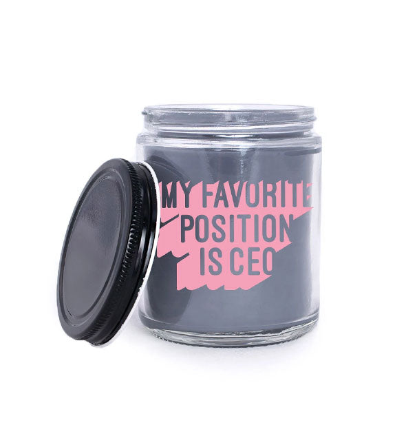 Black wax candle in clear glass jar with black lid says ,"My Favorite Position Is CEO" in pink lettering