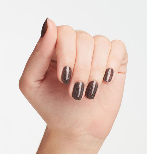 A model's fingernails are painted with deep, shimmery, burgundy-black OPI My Private Jet nail polish.