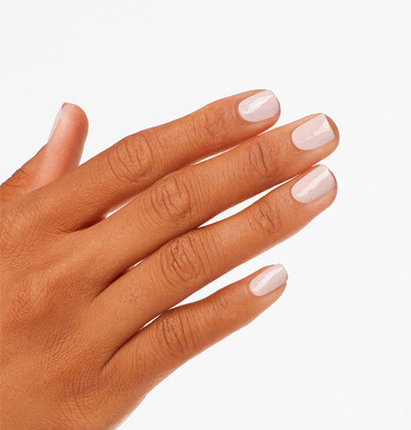 Model's hand wears a light pink shade of nail polish