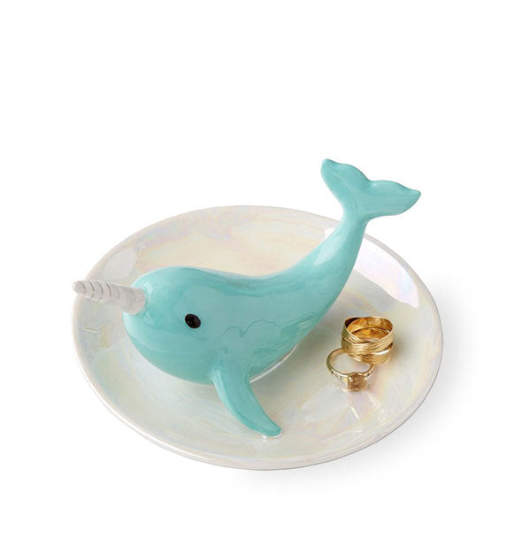 White ceramic dish with narwhal decor holds several gold rings.