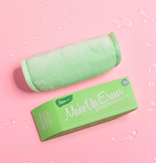 Rolled up Neon Green MakeUp Eraser with box on a pink surface sprinkled with water