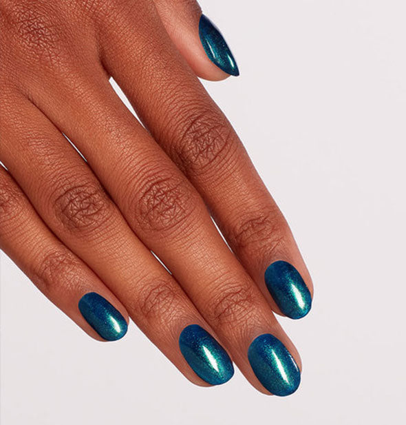 Model's hand wears an iridescent shade of blue-green nail polish