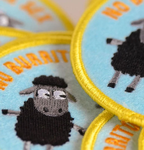 Closeup of rounded embroidered patches with black sheep graphic
