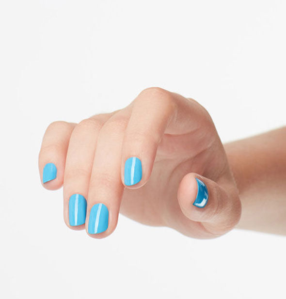 Model's hand wears a sky blue shad of nail polish
