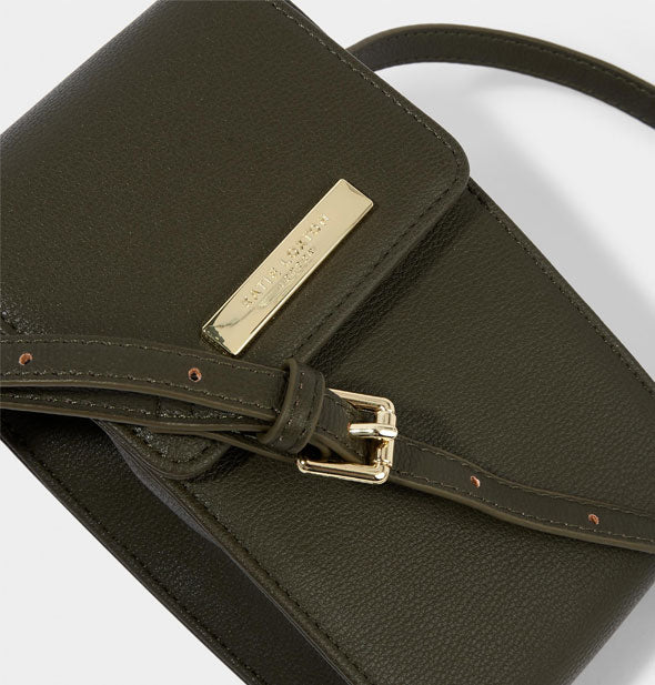 Closeup of dark green Katie Loxton bag with gold label and buckle