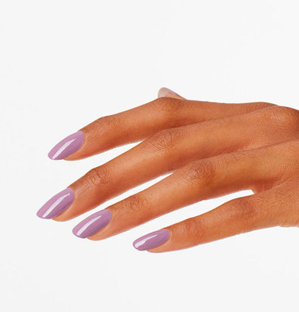 Model's hand wears a dark, muted lilac shade of purple nail polish