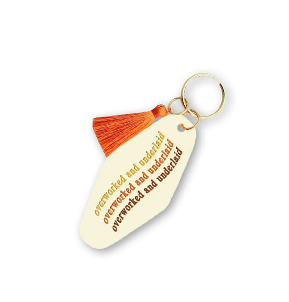 Cream-colored motel-style keychain tab with matching orange tassel says, "Overworked and underlaid" three times in yellow, orange, and brown lettering