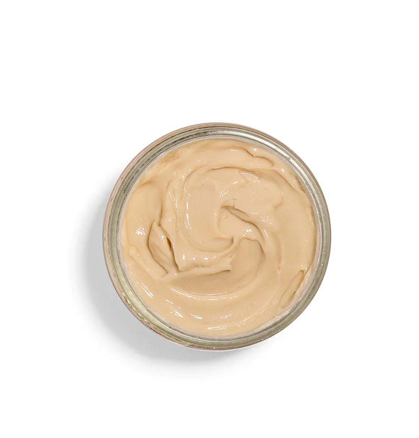 Top view of a pot of face mask with a peachy color and creamy consistency