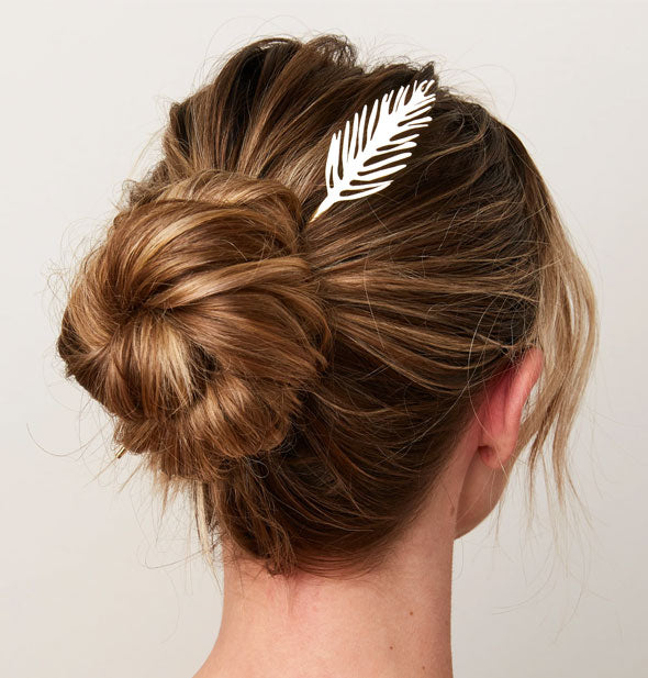 Model wears a brass palm leaf hair pick in a twisted updo