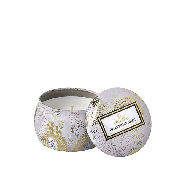 White and gold metallic Panjore Lychee Voluspa candle tin with lid set to the side