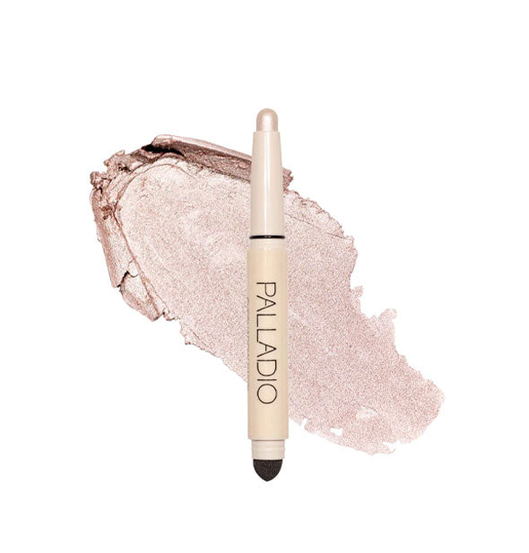 Double-ended Palladio eyeshadow stick with color at one end and black blending sponge at the other rests in front of a color swatch sample in the shade Pearl Shimmer