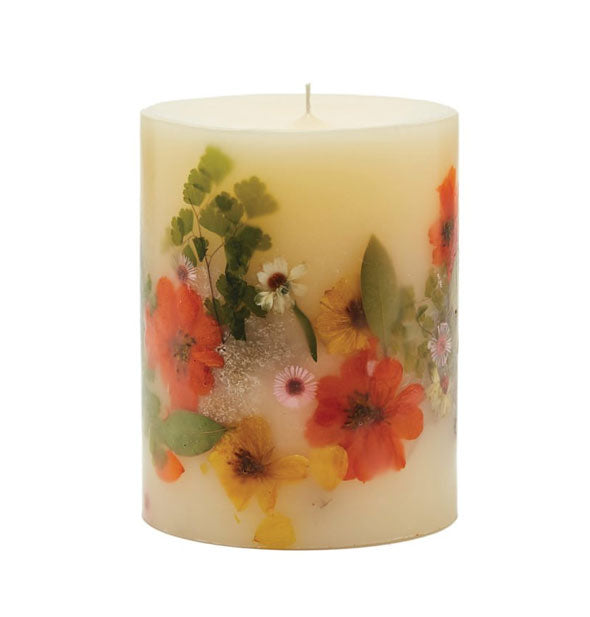 White pillar candle with colorful flowers and leaves embedded in the wax
