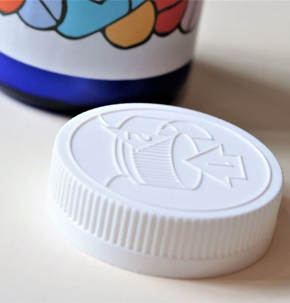 White plastic pill bottle-style cap sits next to pills candle