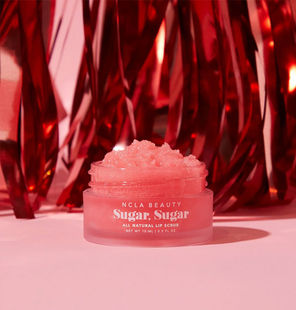 Pot of deep pink NCLA Beauty Sugar, Sugar All Natural Lip Scrub against a backdrop of red tinsel