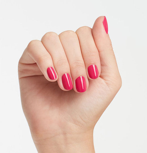 Model's hand wears a medium bright pink shade of nail polish