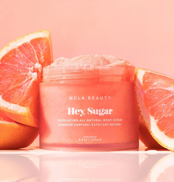 Jar of NCLA Beauty Hey, Sugar body scrub flanked by slices of pink grapefruit