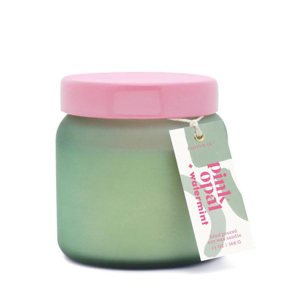 Green glass candle jar with pink lid and hangtag that reads, "Pink Opal + Watermint."