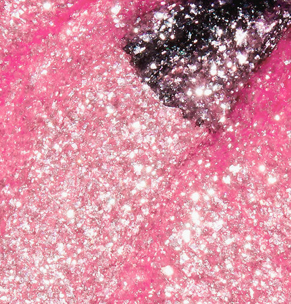 Sparkly pink nail polish with a brush tip swiped through it