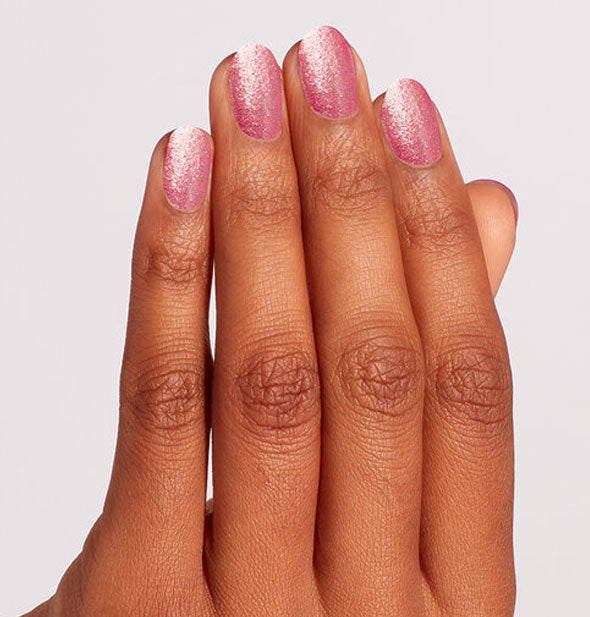 Model's hand wearing a sparkly pink shade of nail polish