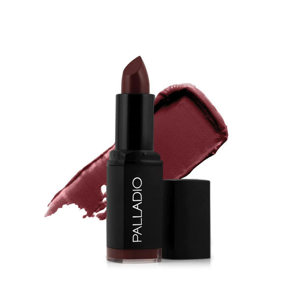 Black tube of Palladio lipstick with cap removed and color swatch behind in a dark wine shade called Plum Majesty