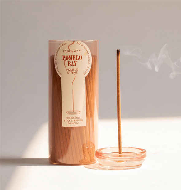 Lid removed from a glass tube of Paddywax Pomelo Bay incense sticks doubles as a holder for one burning stick