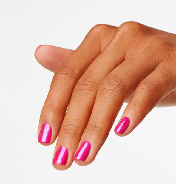 Model's hand wears a shiny shade of bright fuchsia nail polish