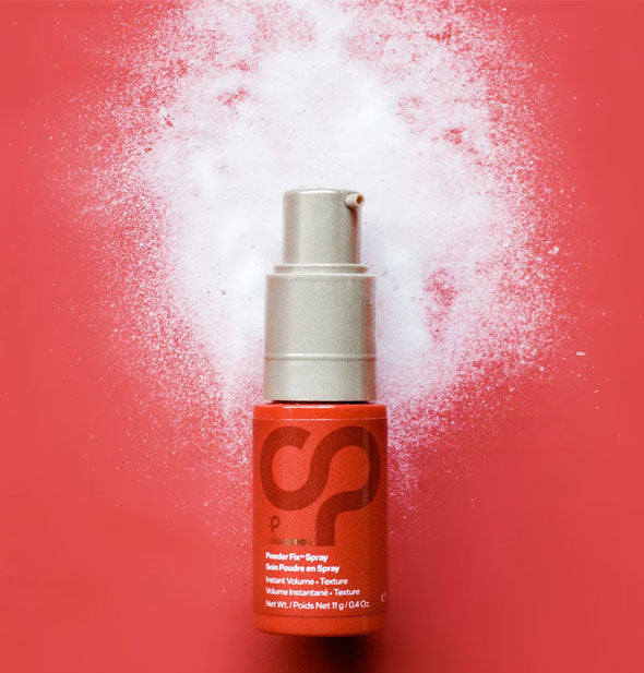 Bottle of ColorProof Powder Fix Spray rests on a red surface dusted with its powdery contents