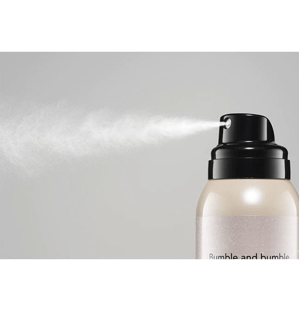 A fine white mist is dispensed from a can of Bumble and bumble Prêt-à-Powder Très Invisible Nourishing Dry Shampoo