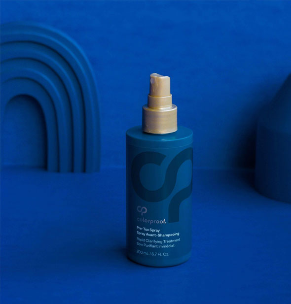 Bottle of ColorProof Pre-Tox Spray staged with monochromatic shapes on a blue background