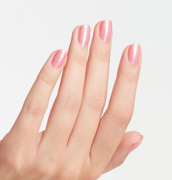 Model's hand wears a pearlescent pink shade of nail polish