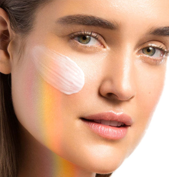 Model has a dense application of Dermalogica Prisma Protect sunscreen on cheek to show product color and consistency