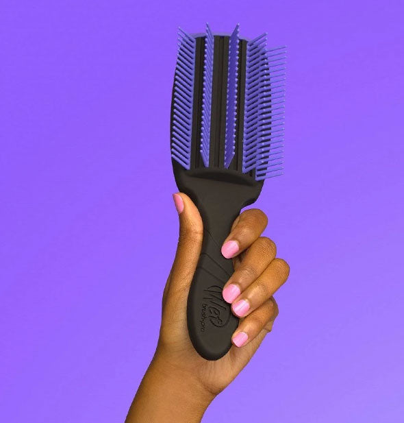 Model's hand holds up a black and purple Wet Brush Pro in front of a purple background