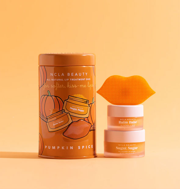 Pumpkin Spice All Natural Lip Treatment Duo by NCLA Beauty includes two small jars of scrub and balm, one textured, lip-shaped scrubber, and one decorative cylindrical tin