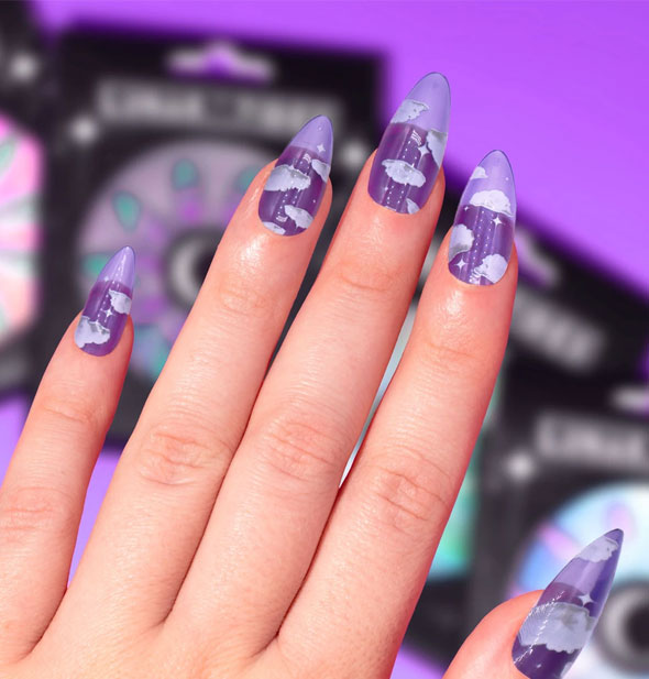 A model's hand displays purple cloud press-on nails