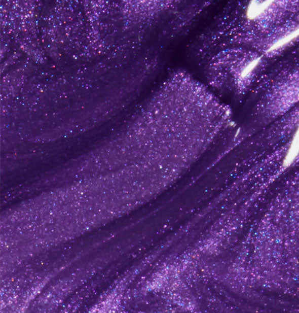 Sparkly purple nail polish with brush tip dipped into it