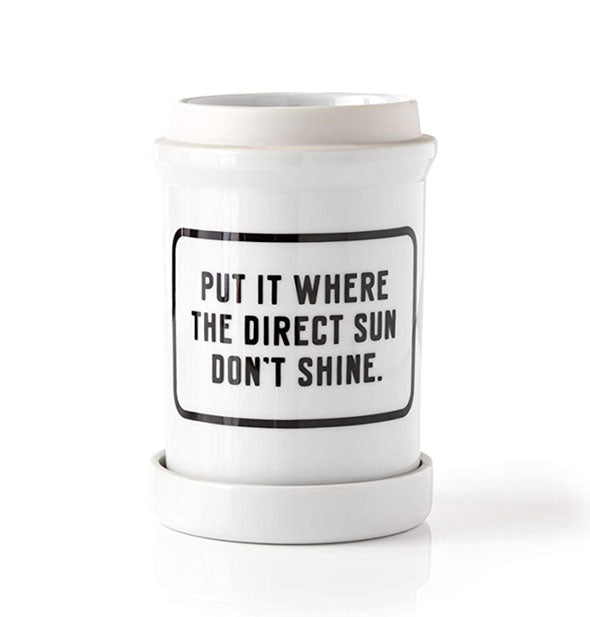 White ceramic pot with dish says, "Put it where the direct sun don't shine" in black lettering inside a black rectangle