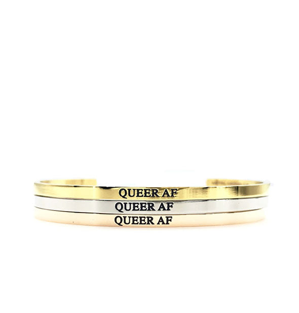 Three stacked Queer AF bangles in gold, silver, and rose gold