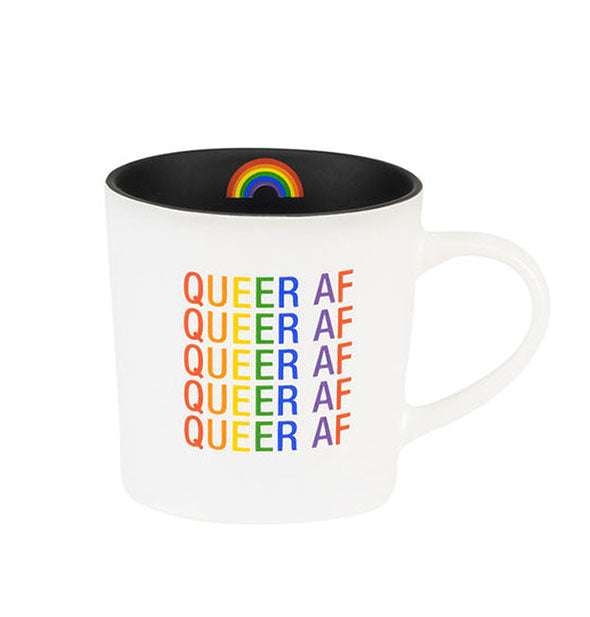 White coffee mug with black interior accented by a rainbow graphic says, "Queer AF" repeated five times in rainbow colored lettering