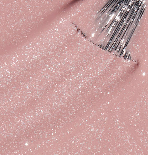 Shimmery pink nail polish with a brush tip swiped through it