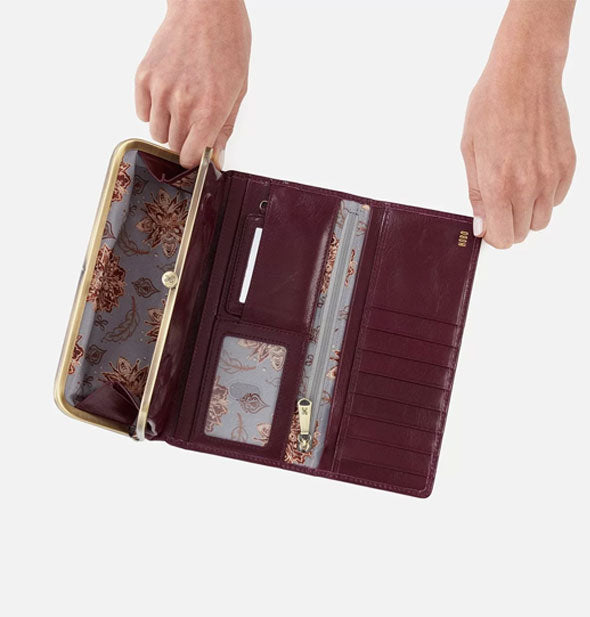 Model's hands hold a maroon leather wallet open to show lining and interior storage compartments
