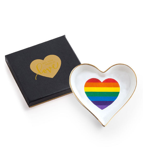 White heart-shaped dish with gold edge and rainbow heart design next to a black gift box with gold heart stamp