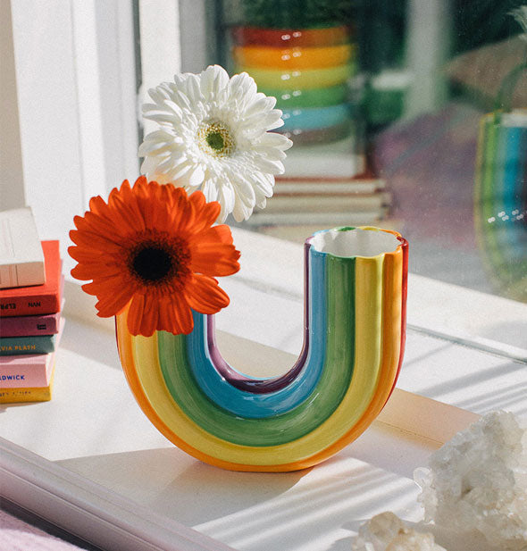Rainbow vase on a window sill has two flowers in its one side