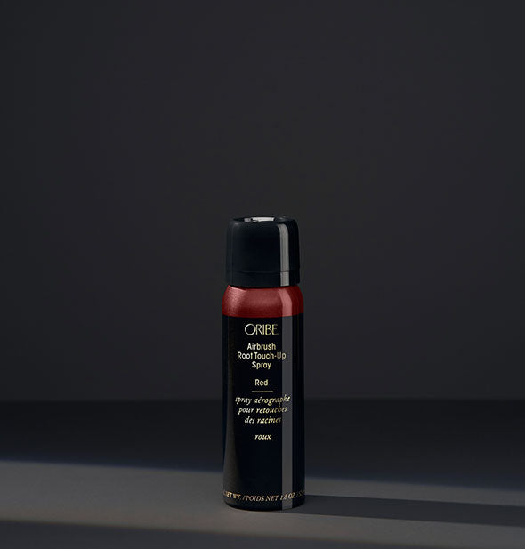 Small can of Oribe Airbrush Root Touch-Up Spray in the shade Red on a dark background