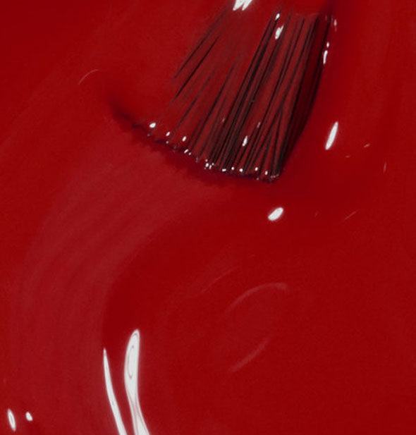 Deep, vibrant red nail polish with brush tip swiped through it