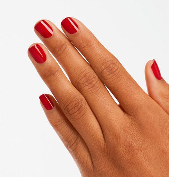 Model's hand wears a red shade of nail polish