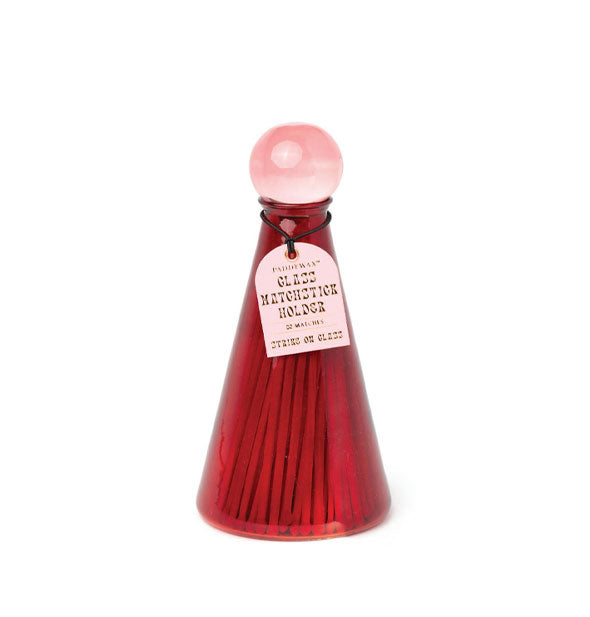 Tapered red glass bottle filled with matchsticks and topped with round pink lid features a pink hang tag that reads, "Glass matchstick holder, 80 matches, strike on glass"